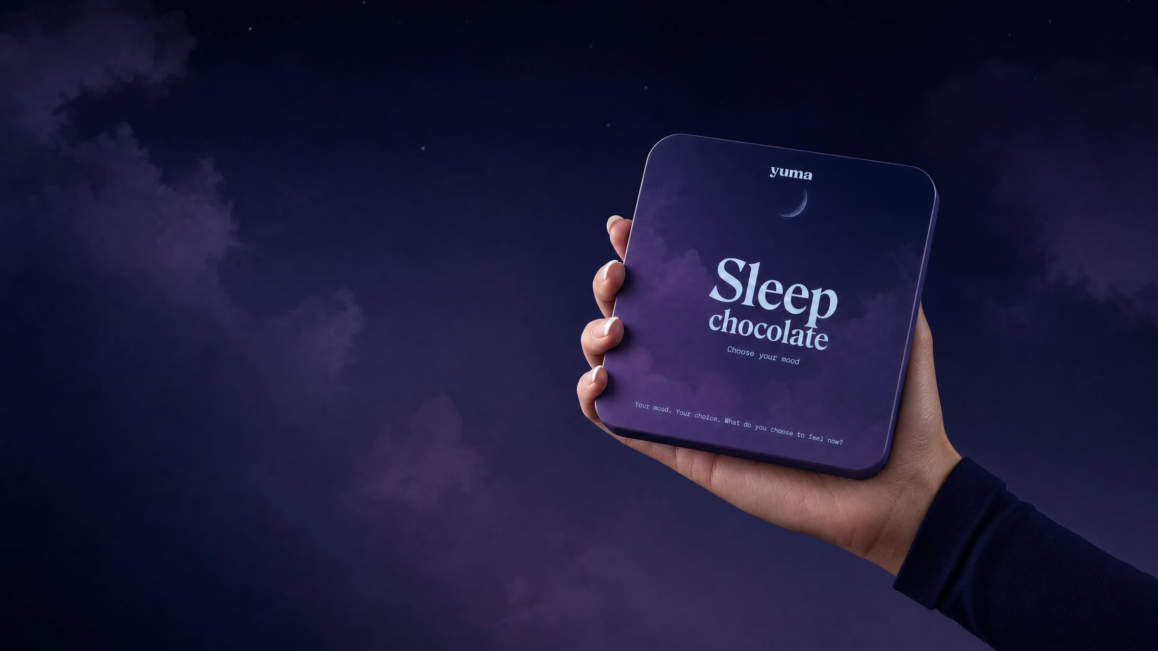 A hand holding a Yuma Sleep chocolate tin against a starry night sky